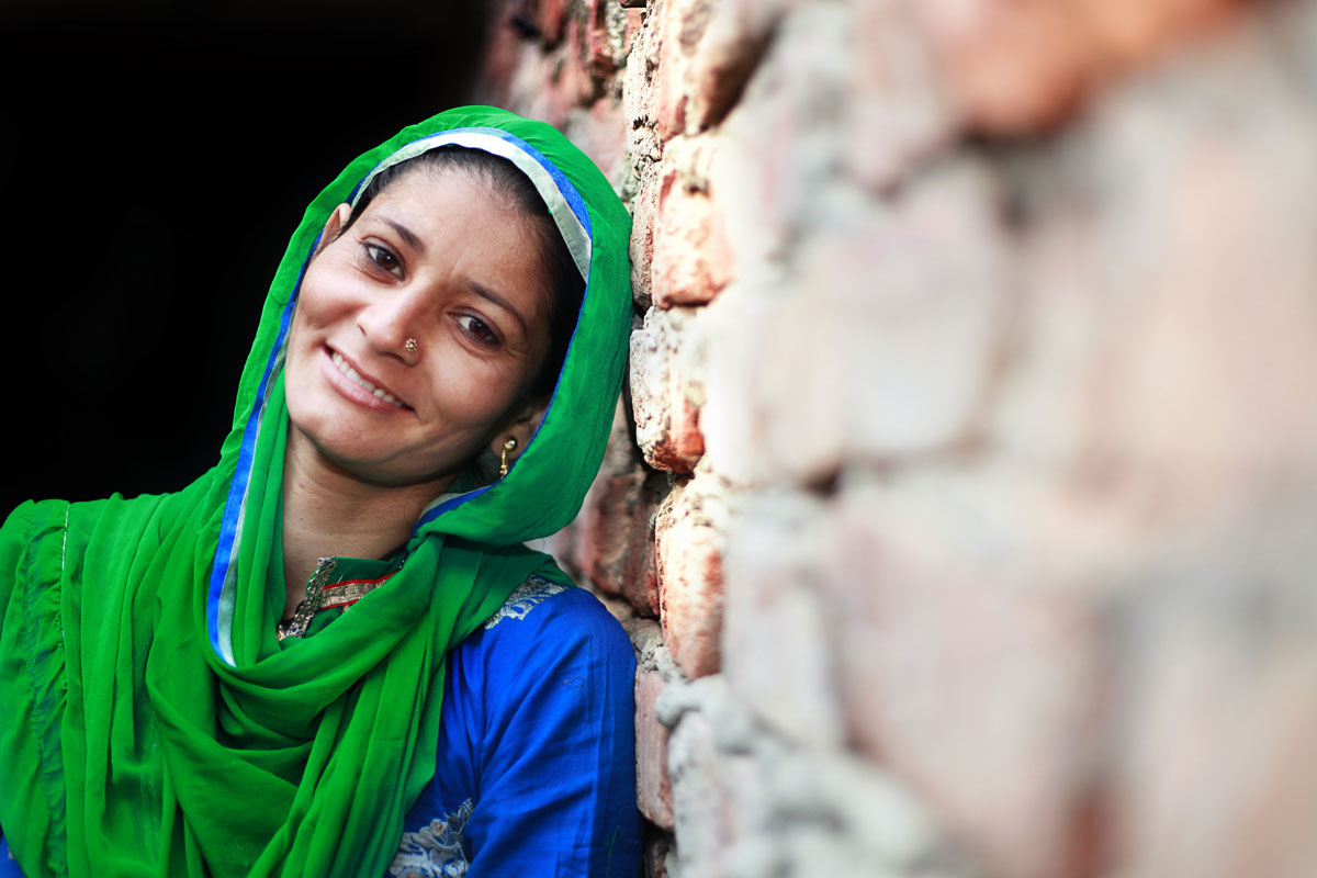 Woman in green scarf by a brick wall