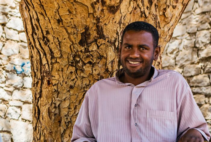 Smiling Muslim man next to a tree