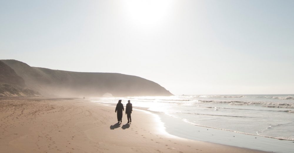 two people walking on beach