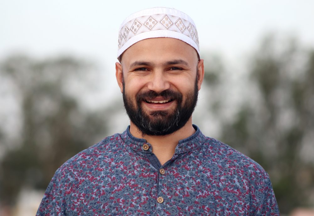 smiling Muslim man in white cap