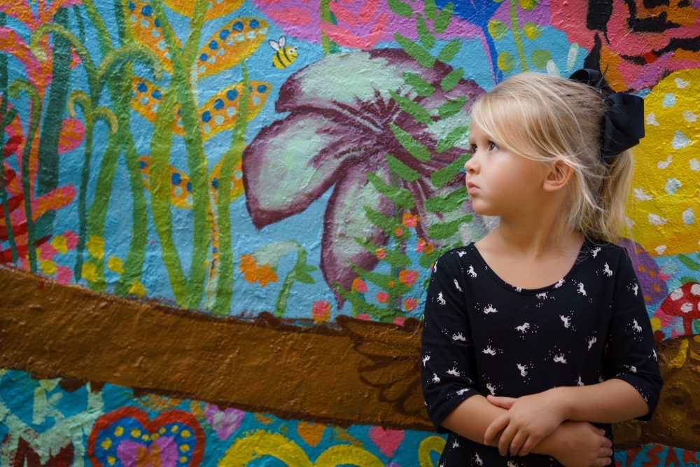 A young girl standing against a painted wall