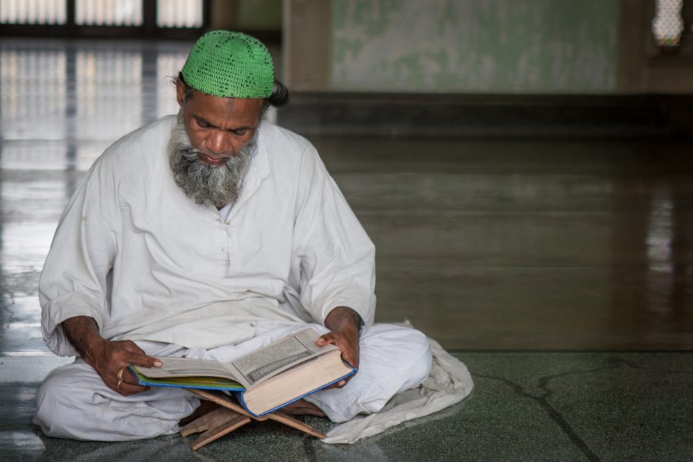 man reading Quran in a mosque