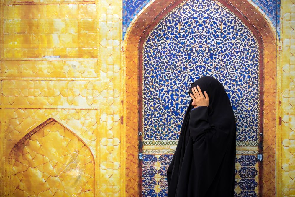 Muslim woman against blue and yellow mosaic